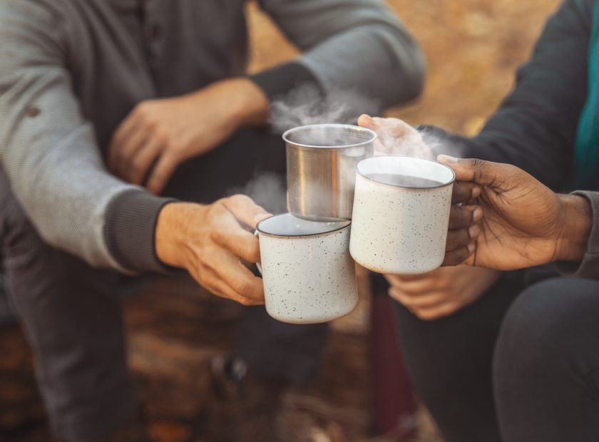 Hands of hikers cheering up with camping cups
